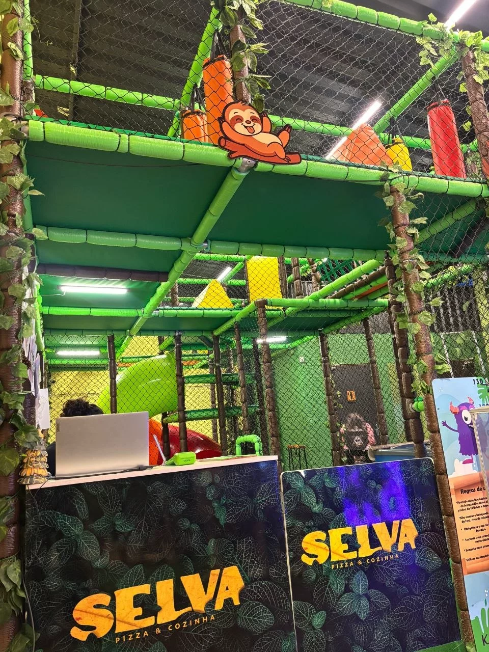 Espaço Kids do Selva Pizzaria — área com brinquedos de madeira, monitores e ambiente climatizado